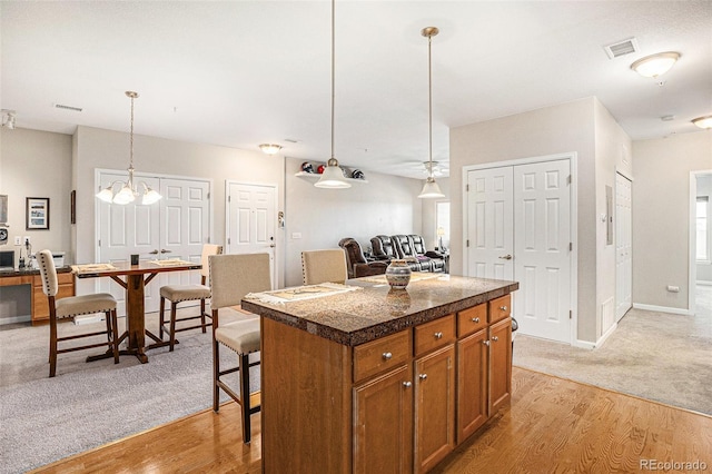 kitchen featuring tile countertops, brown cabinetry, light wood-type flooring, and visible vents