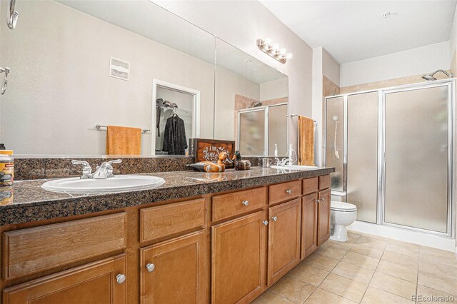 bathroom with double vanity, a stall shower, tile patterned flooring, and a sink