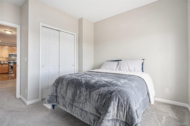 bedroom with baseboards, a closet, and light colored carpet