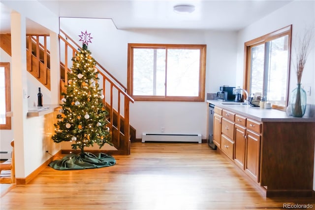 interior space with baseboard heating, light wood-style flooring, stairway, and a sink