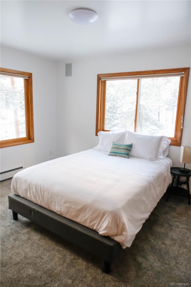 carpeted bedroom with a baseboard heating unit and visible vents