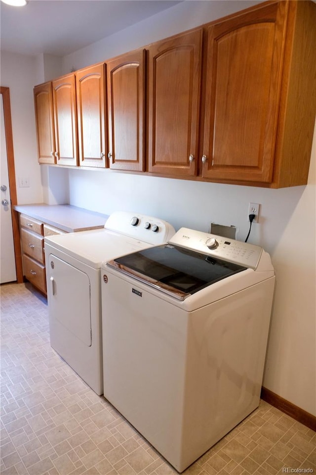 laundry room featuring washer and clothes dryer, cabinet space, and baseboards