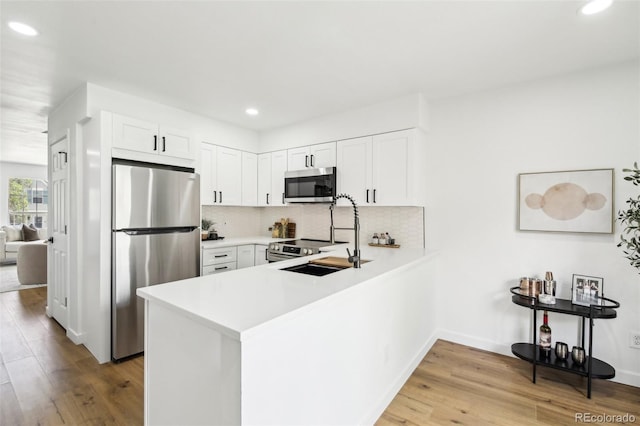 6722 S Independence St, Littleton, CO 80128 - kitchen featuring appliances with stainless steel finishes, recessed lighting, wood finished floors, a peninsula, and a sink