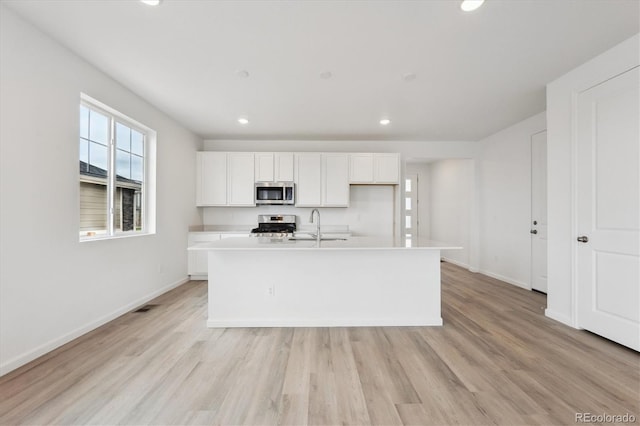 24780 E 39th Ave, Aurora, CO 80019 - kitchen featuring stainless steel appliances, white cabinets, recessed lighting, a center island with sink, and light wood-style floors