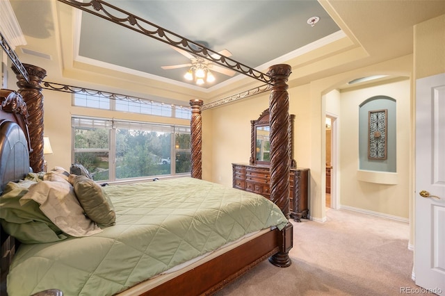 carpeted bedroom with arched walkways, ornamental molding, and a tray ceiling