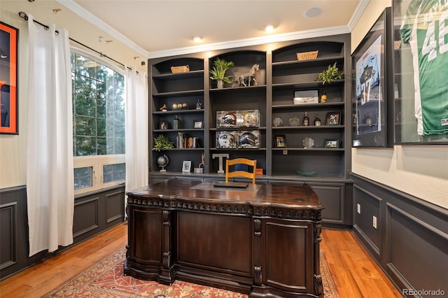 office space featuring light wood-type flooring, ornamental molding, a decorative wall, and a wainscoted wall