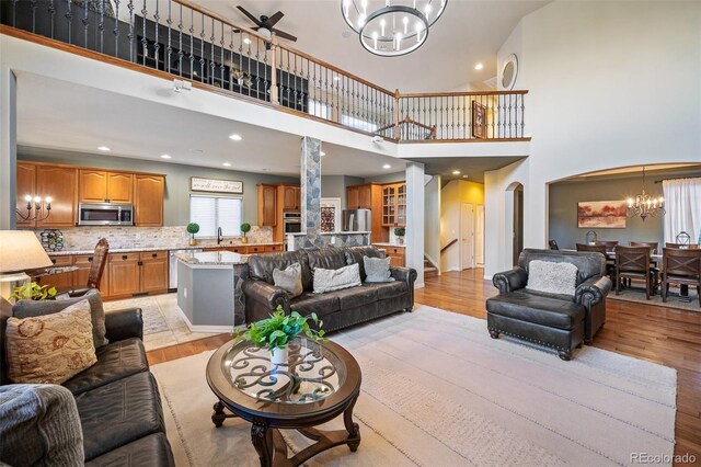 7284 Timbercrest Ln, Castle Pines, CO 80108 - living room with a chandelier, a high ceiling, arched walkways, light wood-style floors, and recessed lighting
