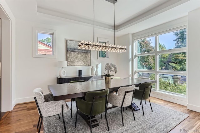 dining room with a tray ceiling, wood-type flooring, and an inviting chandelier