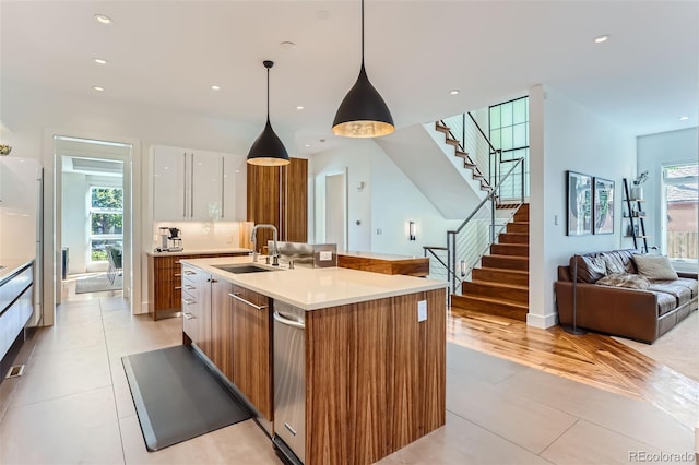 kitchen featuring sink, an island with sink, white cabinetry, hanging light fixtures, and light tile patterned flooring