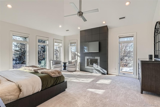 bedroom featuring access to exterior, light carpet, a tile fireplace, and ceiling fan