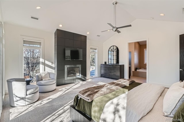 carpeted bedroom featuring connected bathroom, ceiling fan, multiple windows, and a tiled fireplace