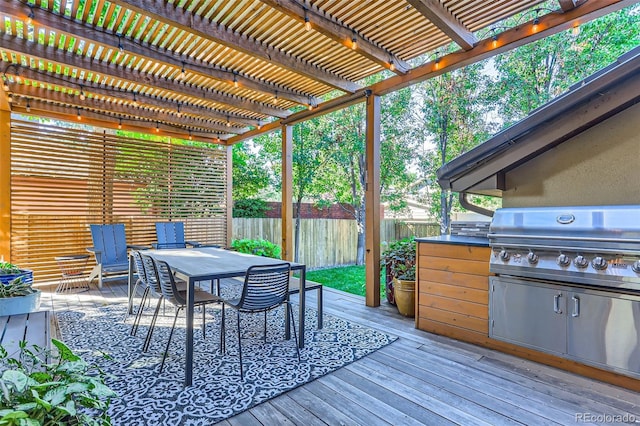 wooden deck featuring a pergola, a grill, and exterior kitchen