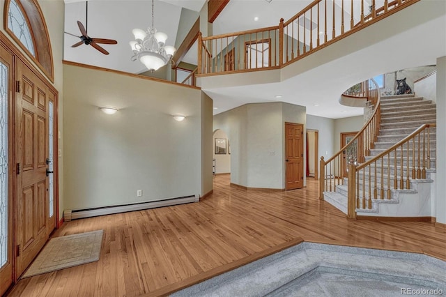 entrance foyer with stairway, wood finished floors, a towering ceiling, and a baseboard radiator