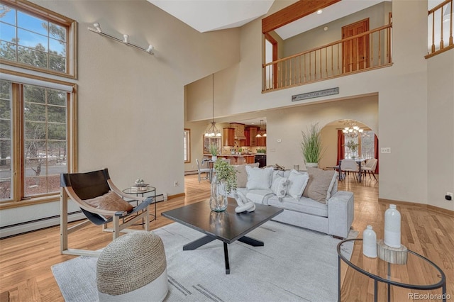 living room featuring baseboards, arched walkways, light wood-type flooring, and a chandelier