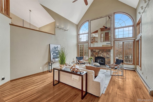 living room with a stone fireplace, high vaulted ceiling, ceiling fan, and wood finished floors