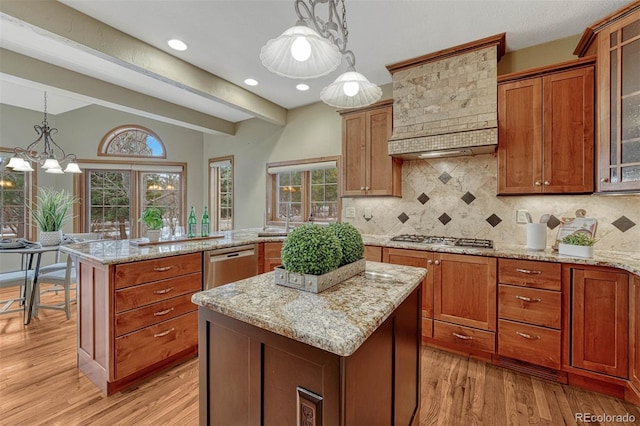 kitchen featuring light wood finished floors, a kitchen island, stainless steel appliances, tasteful backsplash, and brown cabinets