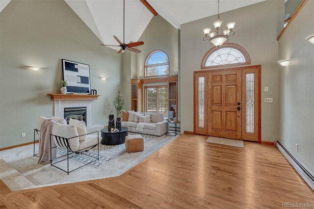 foyer featuring baseboards, a tile fireplace, wood finished floors, high vaulted ceiling, and a baseboard radiator