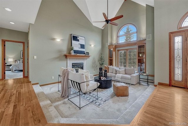 living room with a glass covered fireplace, baseboards, plenty of natural light, and wood finished floors