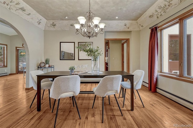 dining space featuring light wood-style flooring, arched walkways, and a baseboard radiator