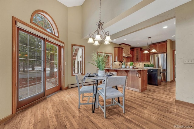 dining space featuring a notable chandelier, baseboards, baseboard heating, and light wood finished floors