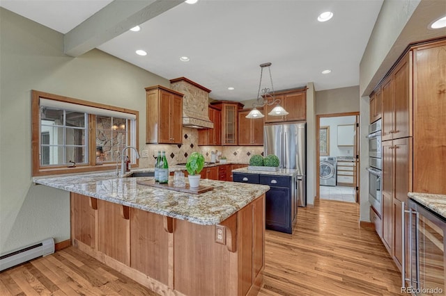 kitchen featuring a baseboard radiator, washer / dryer, a peninsula, brown cabinets, and a sink