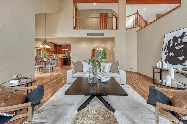 living room with baseboards, a high ceiling, an inviting chandelier, and light wood-style flooring