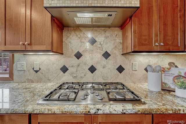 kitchen with tasteful backsplash, stainless steel gas stovetop, and brown cabinetry