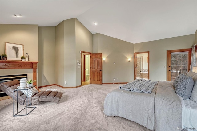 bedroom featuring ensuite bathroom, a tile fireplace, baseboards, light colored carpet, and vaulted ceiling