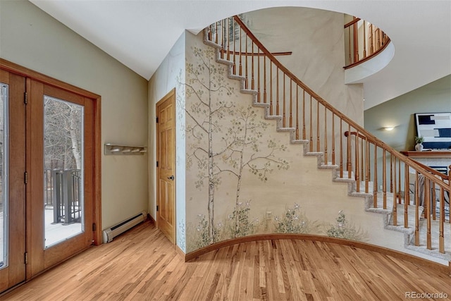 entrance foyer with stairway, wood finished floors, a baseboard radiator, arched walkways, and vaulted ceiling