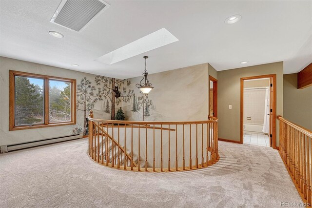 hallway with visible vents, an upstairs landing, baseboard heating, and carpet flooring