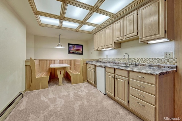 kitchen featuring light brown cabinets, a sink, a baseboard heating unit, white dishwasher, and light colored carpet