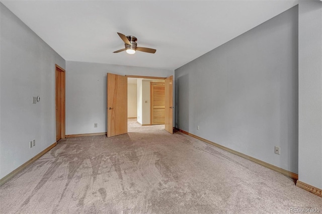 spare room featuring light colored carpet, baseboards, and ceiling fan