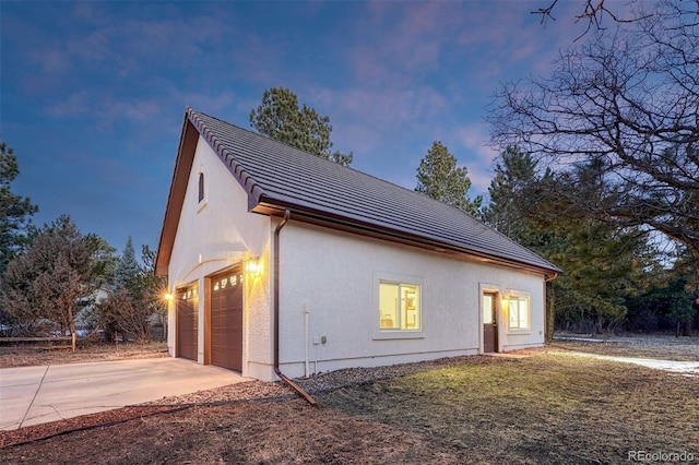 view of home's exterior with stucco siding, a garage, and driveway