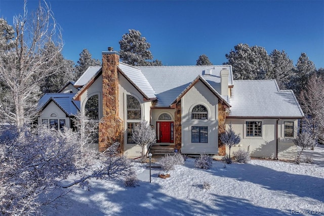 tudor home featuring a tile roof, stucco siding, and a chimney