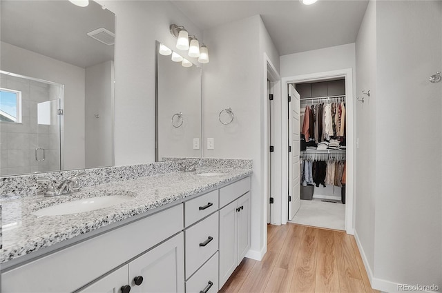 bathroom featuring a shower with door, vanity, and wood-type flooring