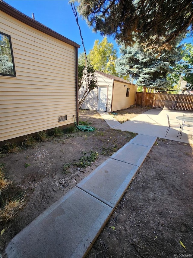 view of yard featuring a storage unit and a patio