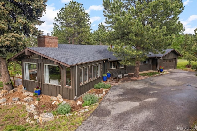 29663 Paint Brush Dr, Evergreen, CO 80439 - view of front of house featuring roof with shingles, a chimney, asphalt driveway, and a garage