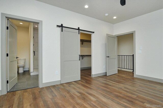 6450 Cleora Rd Unit C, Salida, CO 81201 - unfurnished bedroom featuring a barn door, wood finished floors, a spacious closet, recessed lighting, and a closet