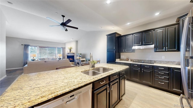 kitchen featuring lofted ceiling, sink, light wood-type flooring, appliances with stainless steel finishes, and light stone countertops