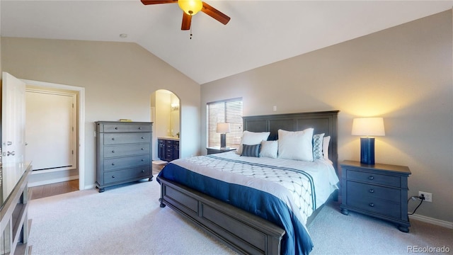 bedroom featuring ceiling fan, lofted ceiling, connected bathroom, and light carpet