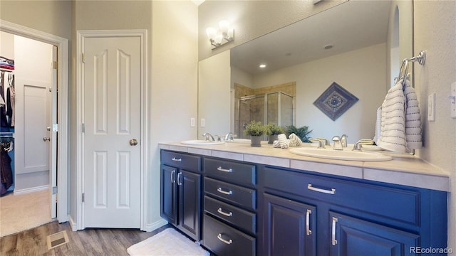 bathroom featuring wood-type flooring, an enclosed shower, and vanity