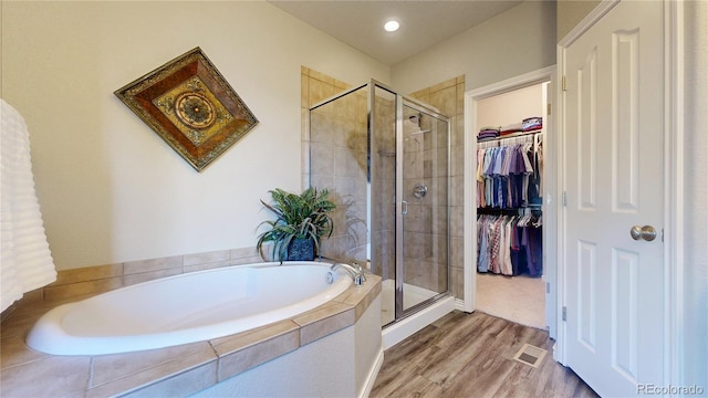 bathroom with independent shower and bath and hardwood / wood-style floors