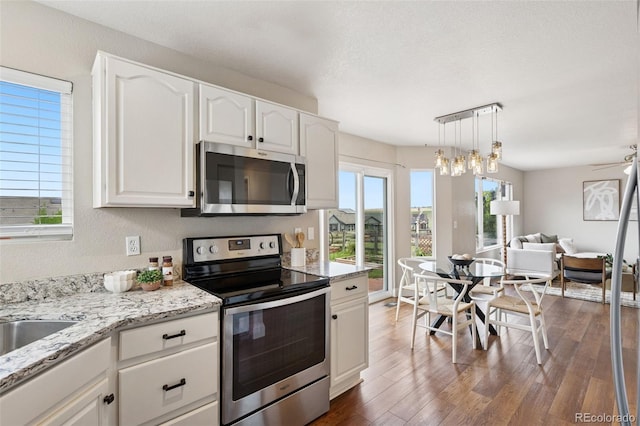 9579 Bighorn Way, Littleton, CO 80125 - kitchen featuring appliances with stainless steel finishes, open floor plan, white cabinetry, light stone countertops, and dark wood-style flooring