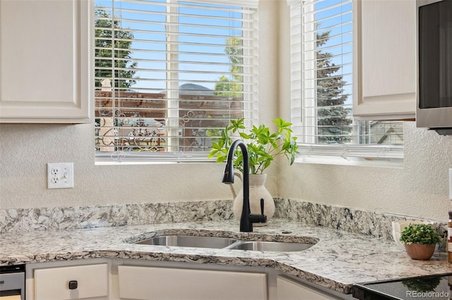 9579 Bighorn Way, Littleton, CO 80125 - kitchen view of a textured wall, stainless steel microwave, light stone counters, and white cabinetry