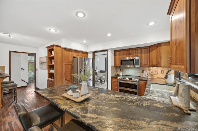 6207 Elbert Pl, Parker, CO 80134 - kitchen featuring appliances with stainless steel finishes, tasteful backsplash, brown cabinets, dark wood-type flooring, and open shelves