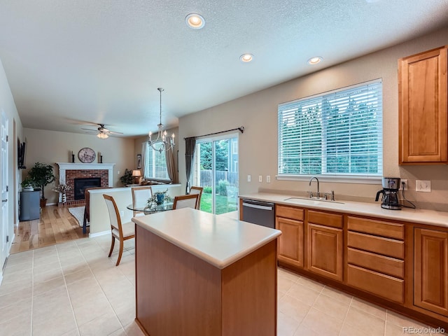 21220 E Nassau Ave, Aurora, CO 80013 - kitchen with a fireplace, light tile patterned flooring, light countertops, a kitchen island, and dishwasher