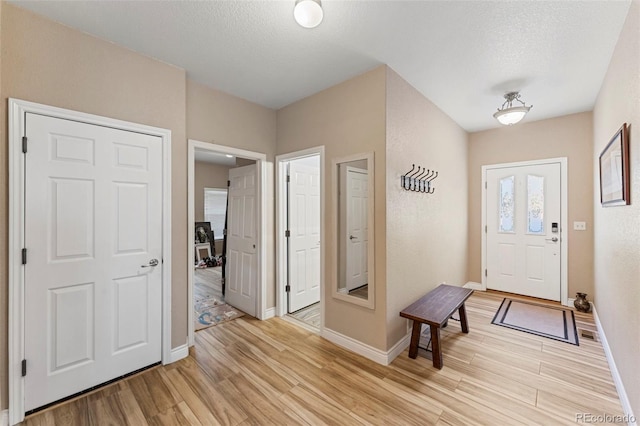 entryway with light wood-type flooring and a textured ceiling