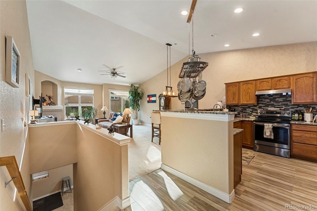 kitchen with ceiling fan, decorative light fixtures, stainless steel electric range oven, a kitchen bar, and decorative backsplash