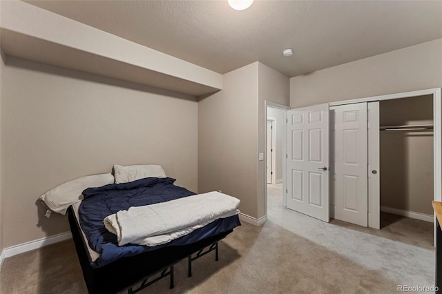 bedroom featuring light colored carpet, a textured ceiling, and a closet