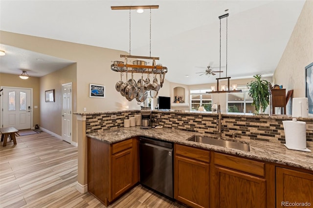 kitchen with light hardwood / wood-style floors, decorative backsplash, stainless steel dishwasher, and sink